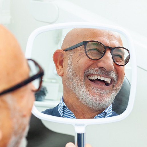 Man with black glasses smiling in reflection in mirror
