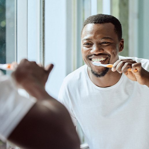 Man smiling while brushing his teeth