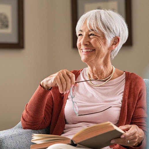 Senior woman smiling while reading at home