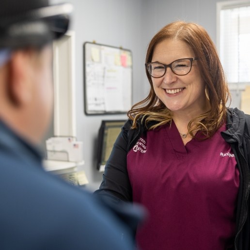 Dental team member smiling at dental patient at front desk