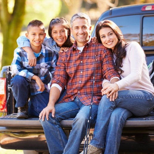 Smiling family of four sitting in truck bed