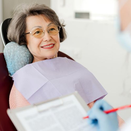 Dentist taking notes during senior patient’s consultation