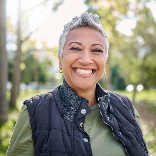 Senior woman standing in a park and smiling