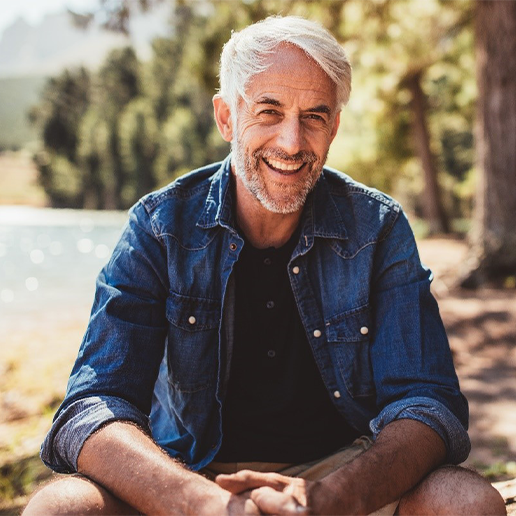 Senior man sitting in the woods and smiling