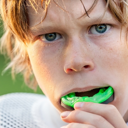 Young boy placing athletic mouthguard in his mouth