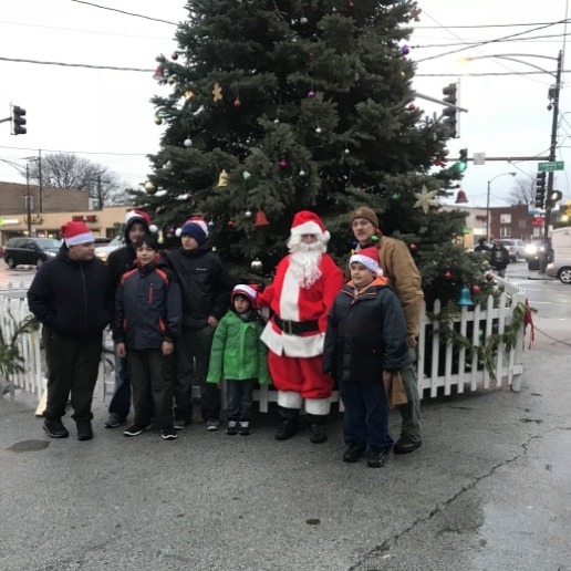 Merrillville dentist dressed up as Santa standing in front of Christmas tree on sidewalk