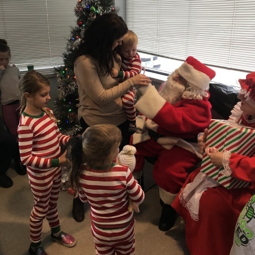 Dentist dressed as Santa Claus giving candy canes to children