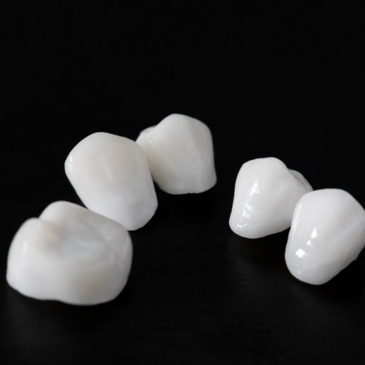 Five lifelike dental crowns in front of black background