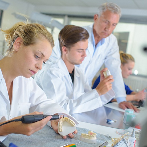 Lab technicians in white coats building dentures