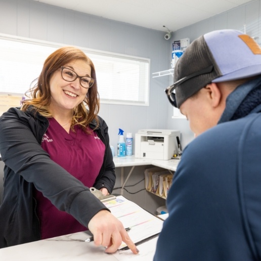 Dental team member pointing to paperwork where a dental patient needs to sign