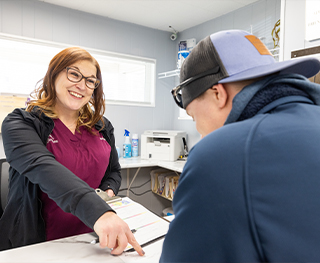 Dental team member pointing to paperwork where a dental patient needs to sign