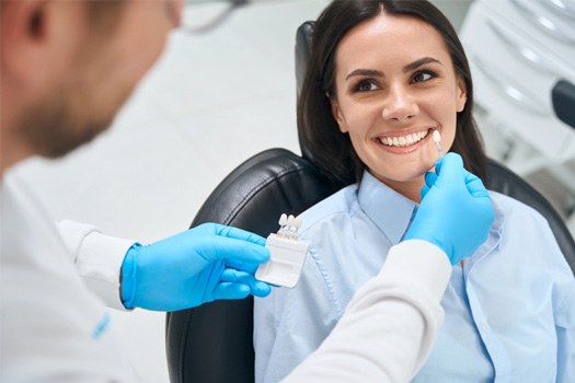 Dentist holding single shade-guide sample to woman’s smile