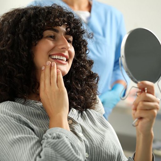 Happy patient admiring her smile in mirror