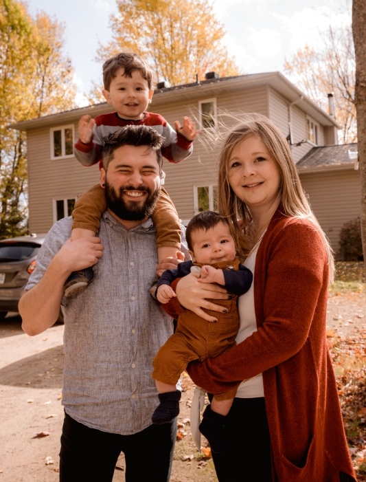 Family of four smiling in their front yard after receiving dental services in Merrillville