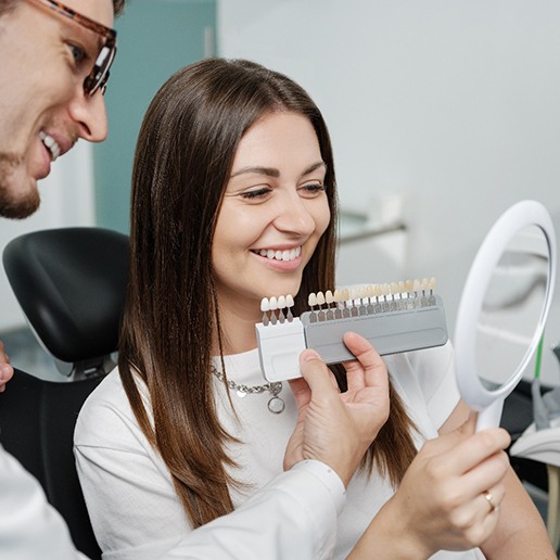 Cosmetic dentist and patient smiling while selecting shade of veneers