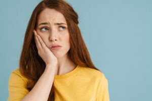 Woman holding jaw in pain.