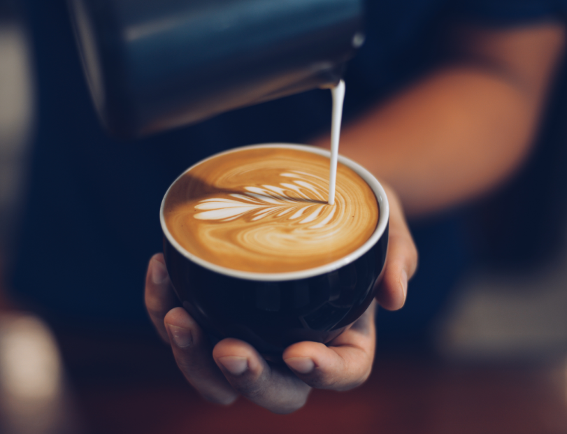 Barista pouring milk into a latte